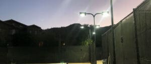 Outdoor tennis court at dusk with lights.