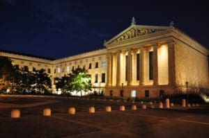 A large building with columns and lights on the side.