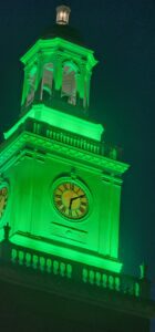 Clock tower glowing green at night.