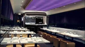 Modern restaurant with purple ceiling and booths.