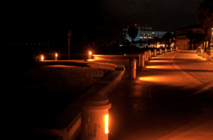 Nighttime boardwalk lights, ocean view.