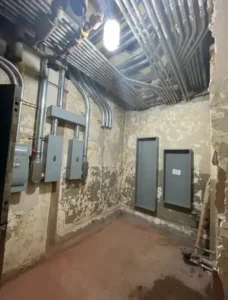 Basement room with exposed pipes and panels.